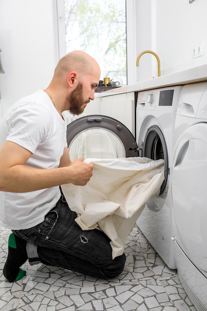 Mann legt Wäsche in eine Waschmaschine