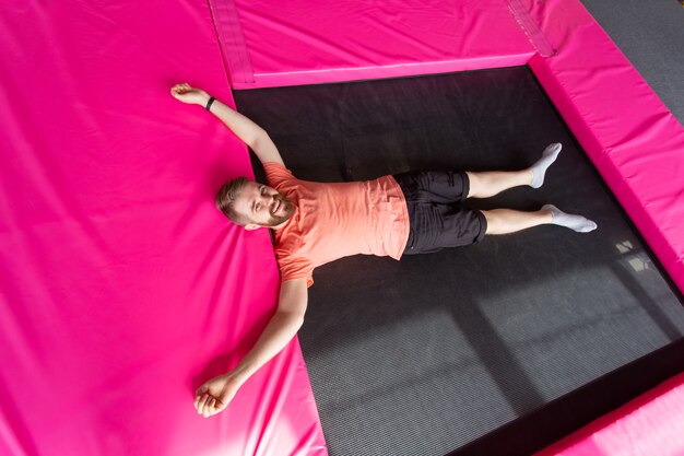 Mann liegt auf einem Trampolin drinnen, Ansicht von oben