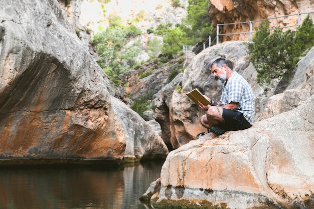 Mann liest ein Buch, während er die Ruhe des Berges genießt