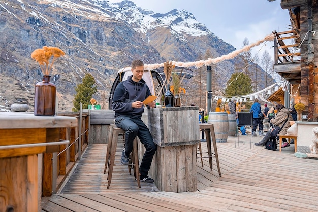 Mann liest Menükarte, während er im Restaurant im Freien gegen den Berg sitzt