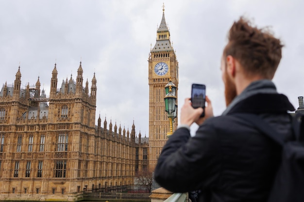 Mann macht ein Foto von Big Ben und dem Westminster-Palast auf dem Smartphone