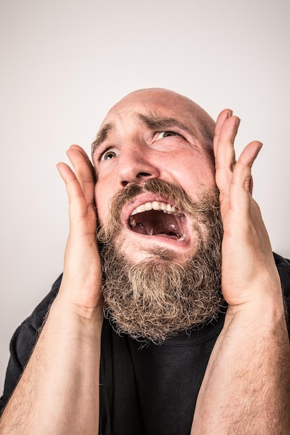 Foto mann macht ein gesicht, während die hände die ohren gegen die wand bedecken