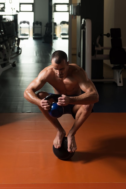 Mann macht Kettle Bell-Übung auf Medizinball