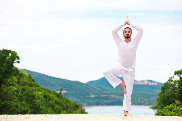 Mann macht klassische indische Kunst Yoga am Meer und in den Bergen