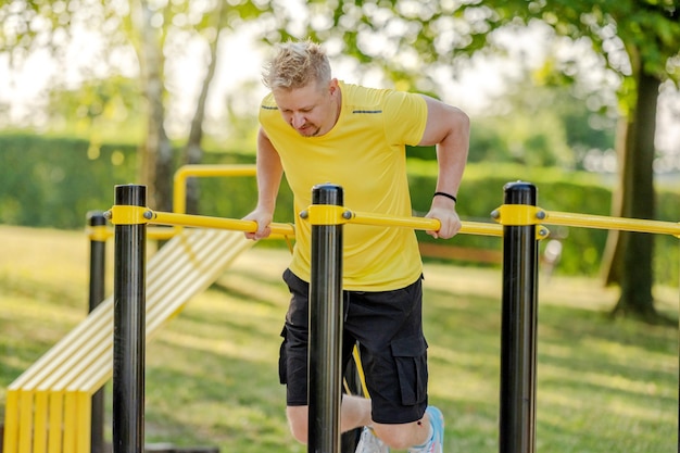 Mann macht Liegestütze mit horizontaler Stange im Freien im Park für gesundes Wohlbefinden und Armtraining