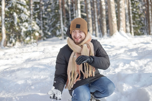 Mann macht Schneeball im verschneiten Wald