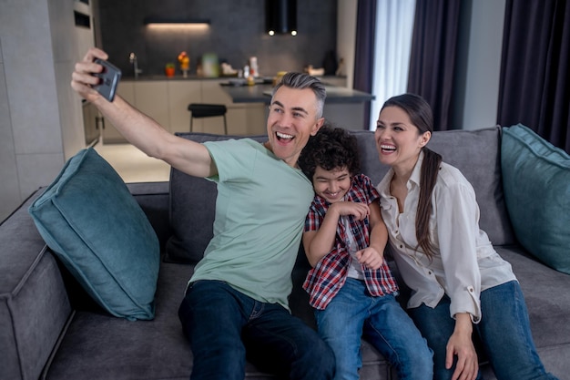 Mann macht Selfie mit Frau und Sohn auf dem Smartphone
