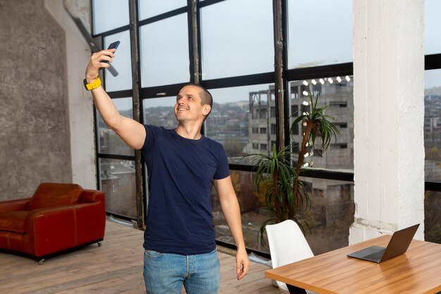 Mann macht Selfie zu Hause oder im Coworking-Büro. Legerer Indoor-Platz.