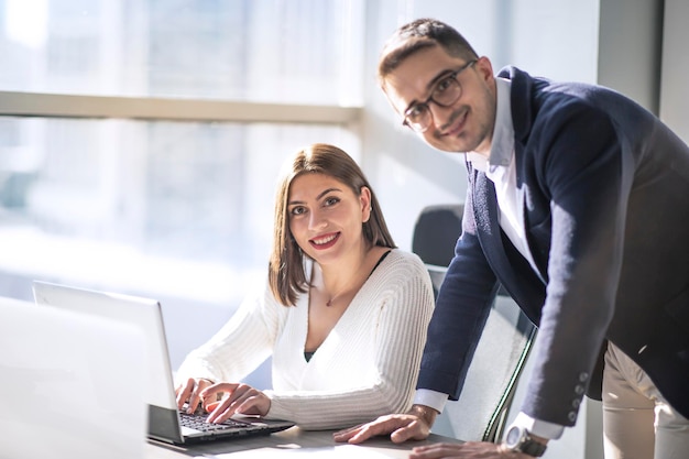 Mann-Manager und Datenanalytikerin, die in einem modernen Büro mit selbstbewusster Stimmung lächelnd in die Kamera schauen