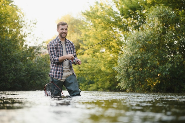 Mann mit Angelrute Fischermänner im Flusswasser im Freien Fangen von Forellenfischen im Netz Sommer-Fischerei-Hobby