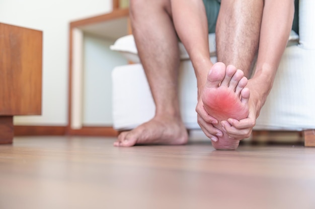 Mann mit Barfußschmerzen aufgrund von Plantarfasziitis und Bunion-Zehen oder Blasen aufgrund des Tragens schmaler Schuhe und des Aufwachens oder Laufens über lange Zeit Gesundheits- und medizinisches Konzept