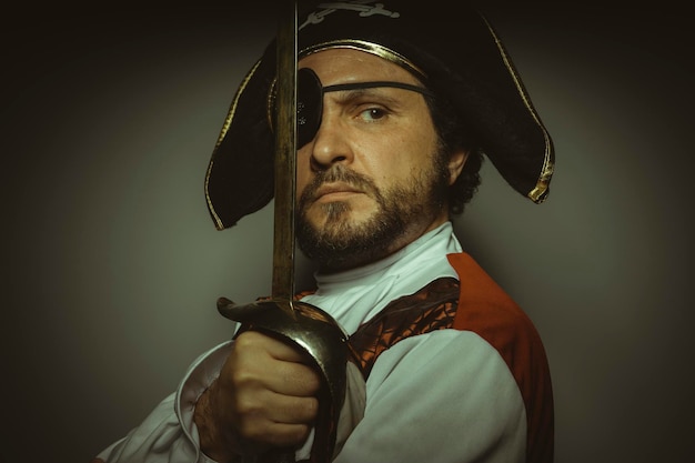 Mann mit Bart, gekleidet wie ein Pirat, mit Augenklappe und Stahlschwert