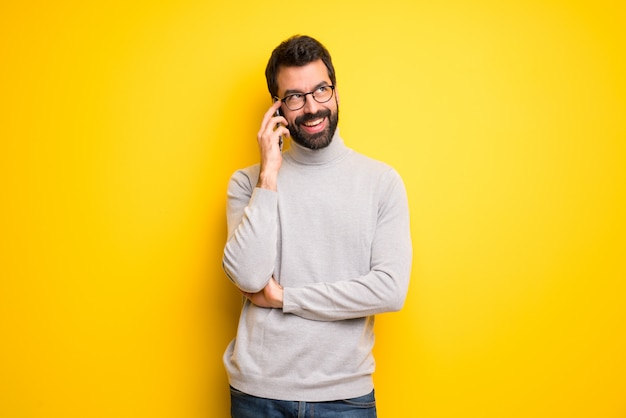 Mann mit bart und rollkragenpullover, die ein gespräch mit dem mobiltelefon führen