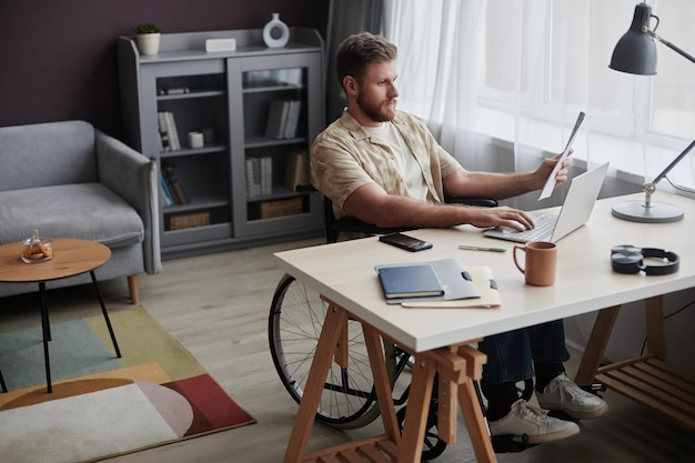 Foto mann mit behinderung, der von zu hause aus arbeitet und dokumente liest