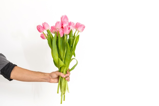 Mann mit Blumen. Romantischer Mann mit Tulpenstrauß zum Geburtstag. Glücklicher Frauentag. Blumenstrauß schenken. Gut aussehender Mann, der Blumen gibt. Weißer Hintergrund. Horizontales Foto.s