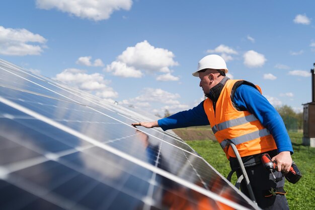 Mann mit Bohrschrauber installiert Paneele in einem Solarkraftwerk
