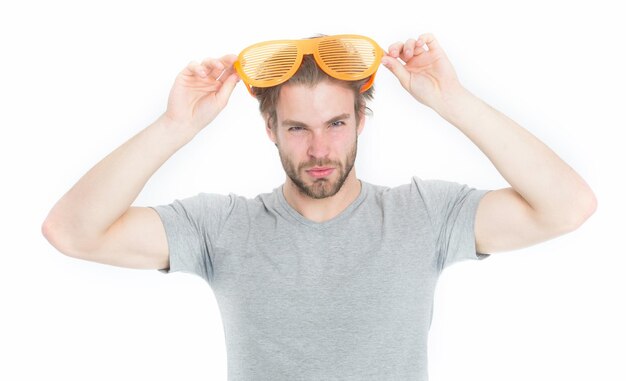 Mann mit Brille Junger Mann im grauen Hemd posiert mit lustiger orangefarbener großer Partybrille isoliert auf weißem Hintergrund Firmenfeierkonzept