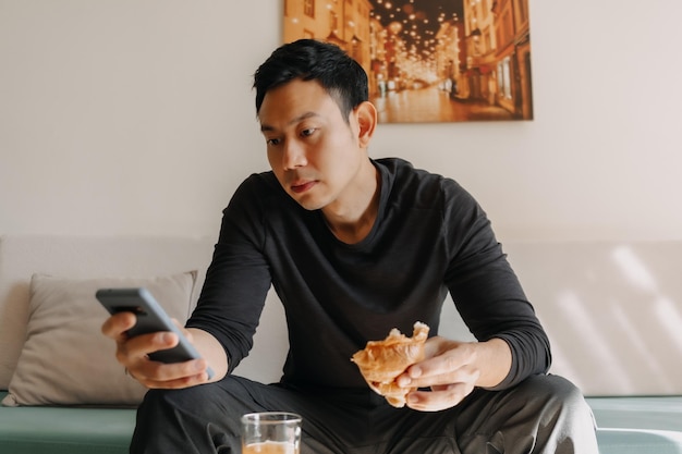 Mann mit Brot und Saft als Frühstück auf dem Sofa im Wohnzimmer