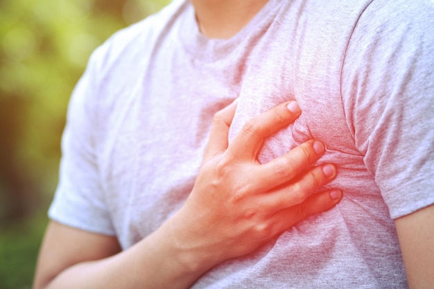 Mann mit Brustschmerzen - Herzinfarkt verursacht eine Schockerkrankung des Körpers auf dem Sofa im Wohnzimmer. oder Koliksäure fließt zurück in die Brust. Gesundheitskonzept.