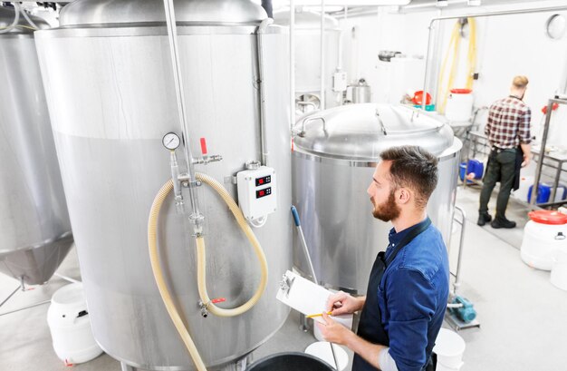 Foto mann mit clipboard in einer brauerei oder bierfabrik