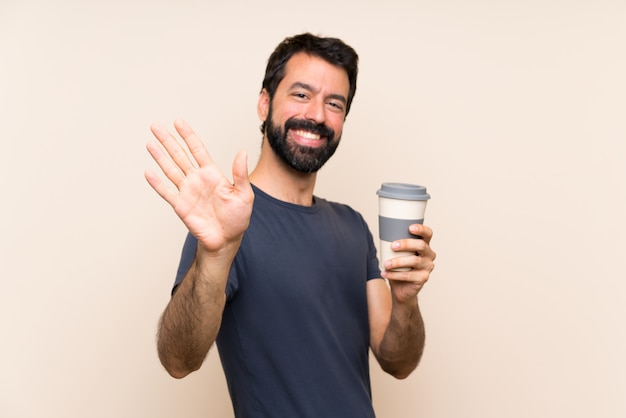 Mann mit dem Bart, der einen Kaffee begrüßt mit der Hand mit glücklichem Ausdruck hält