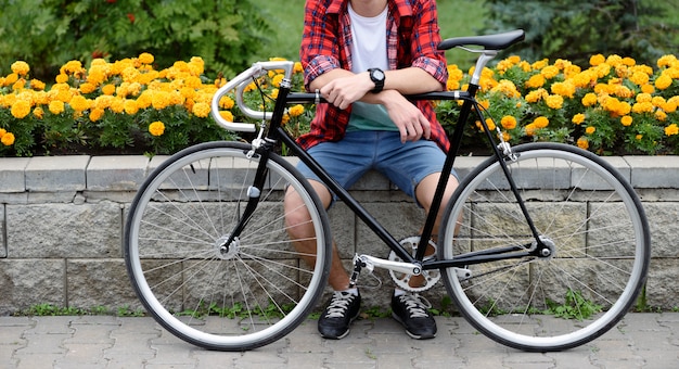 Mann mit dem Fahrrad, das über Blumenbeet mit gelben Blumen ruht