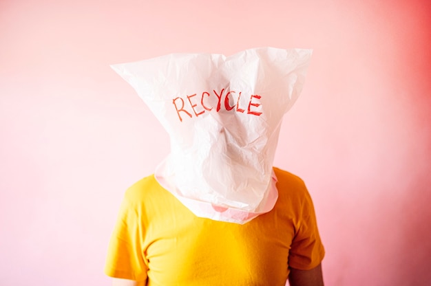 Mann mit dem Kopf von einer Plastiktüte mit dem Wort RECYCLE bedeckt