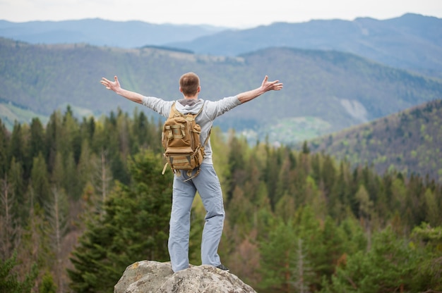 Mann mit dem Rucksack, der auf der Spitze eines Felsens steht