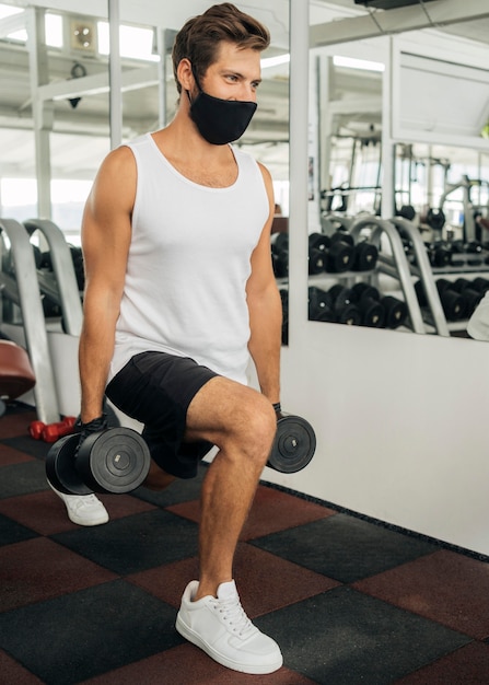 Mann mit der medizinischen Maske, die an der Turnhalle arbeitet