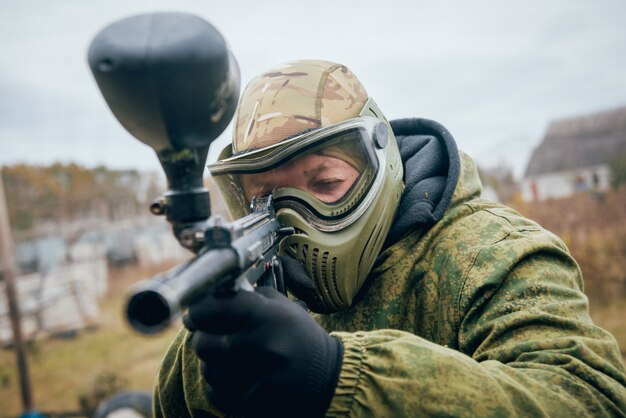 Mann mit der Waffe, die am Paintball spielt. Draußen