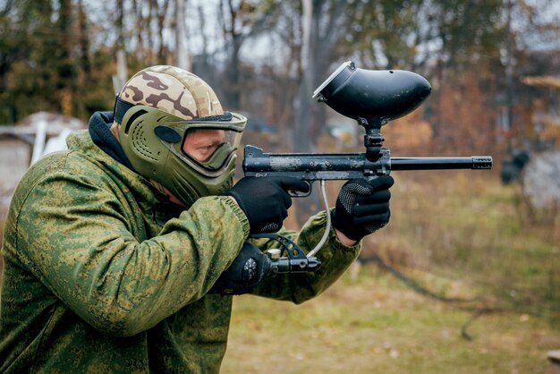 Foto mann mit der waffe, die am paintball spielt. draußen