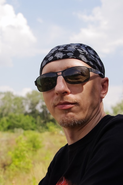 Mann mit dunkler Brille und einem Bandana auf dem Kopf