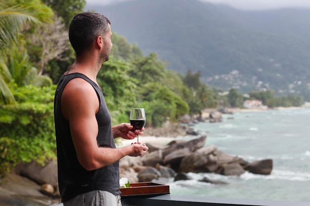 Mann mit einem Glas, der auf das Meer blickt