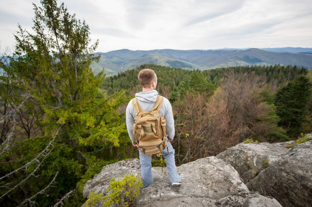 Mann mit einem Rucksack, der am Rand eines Felsens steht