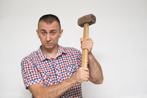 Foto mann mit einem vorschlaghammer an einer weißen wand