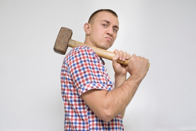 Foto mann mit einem vorschlaghammer an einer weißen wand