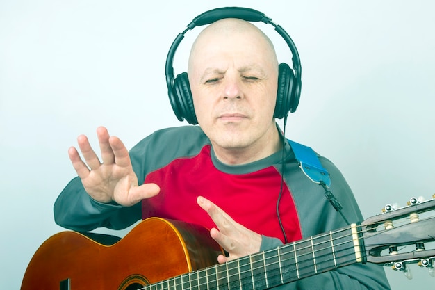 Mann mit einer klassischen Gitarre und Kopfhörern auf dem Kopf, der Musik hört