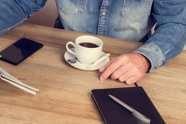 Mann mit einer Tasse Kaffee an seinem Schreibtisch