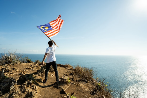 Mann mit Flagge von Malaysia oben auf Berg