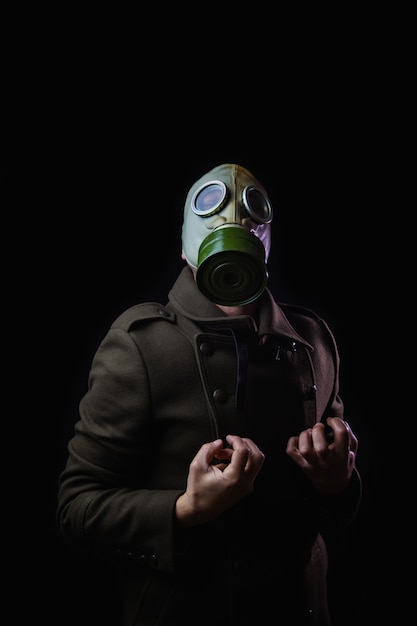 Mann mit Gasmaske in der Schmerzposition auf schwarzem Hintergrund