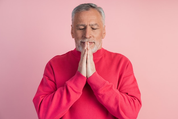 Mann mit geschlossenen Augen meditiert über eine rosa Wand