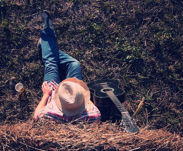 Mann mit Gitarre und Bier über die Natur