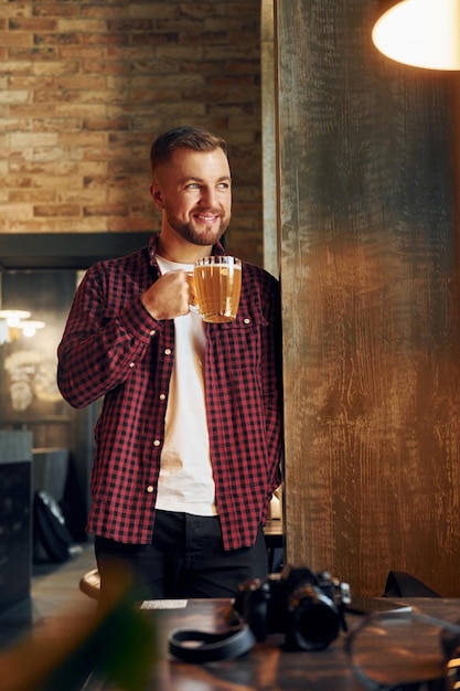 Mann mit Glas Bier steht in der Bar und lächelt