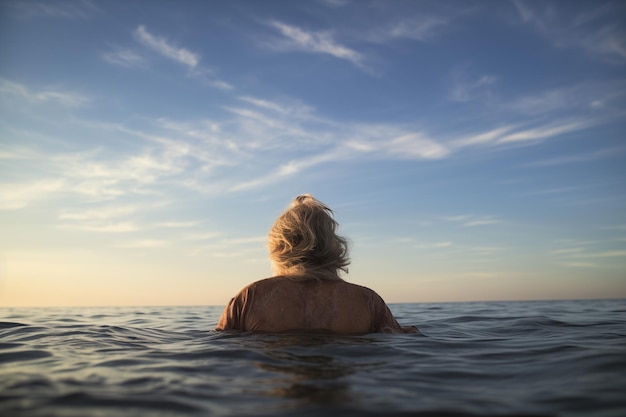 Mann mit grauen Haaren und T-Shirt badet im Meer mit klarem Himmel