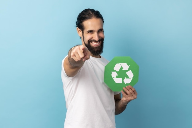 Mann mit grünem Recycling-Schild, das auf die Kamera zeigt, ruft dazu auf, unseren Planeten vor Umweltverschmutzung zu retten