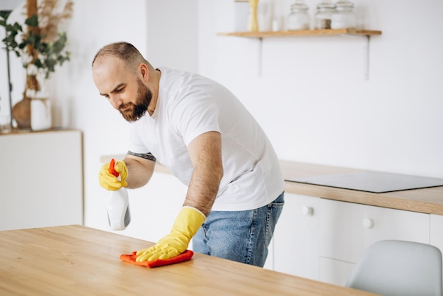 Mann mit Gummihandschuhen beim Aufräumen in der Küche