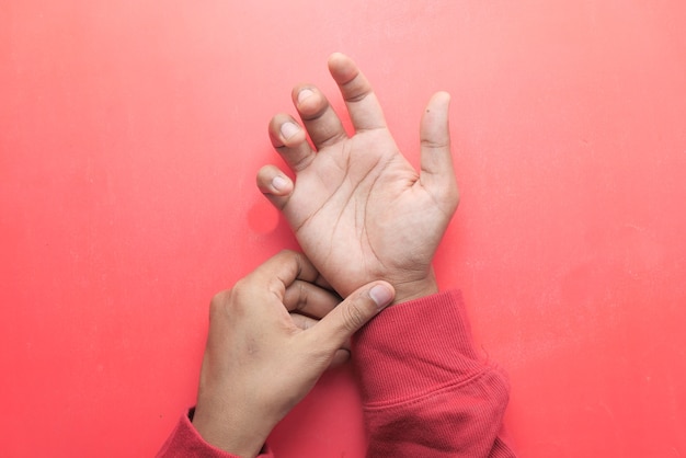 Mann mit Handschmerzen auf rotem Hintergrund