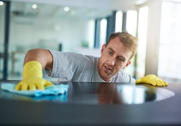 Foto mann mit handschuhen reinigt die oberfläche im büro. gesundheit und hygiene am arbeitsplatz. hausmeister am sauberen schreibtisch. professioneller reiniger, der den tisch am arbeitsplatz abwischt. wartung und desinfektionsmittel auf einem tuch für keime