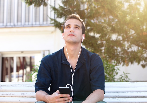 Mann mit Handy und Kopfhörern, die oben schauen