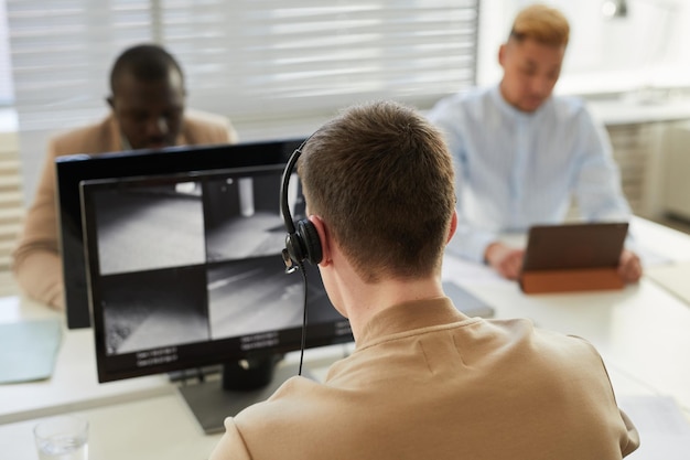 Mann mit Headset, der sich Überwachungsaufnahmen ansieht